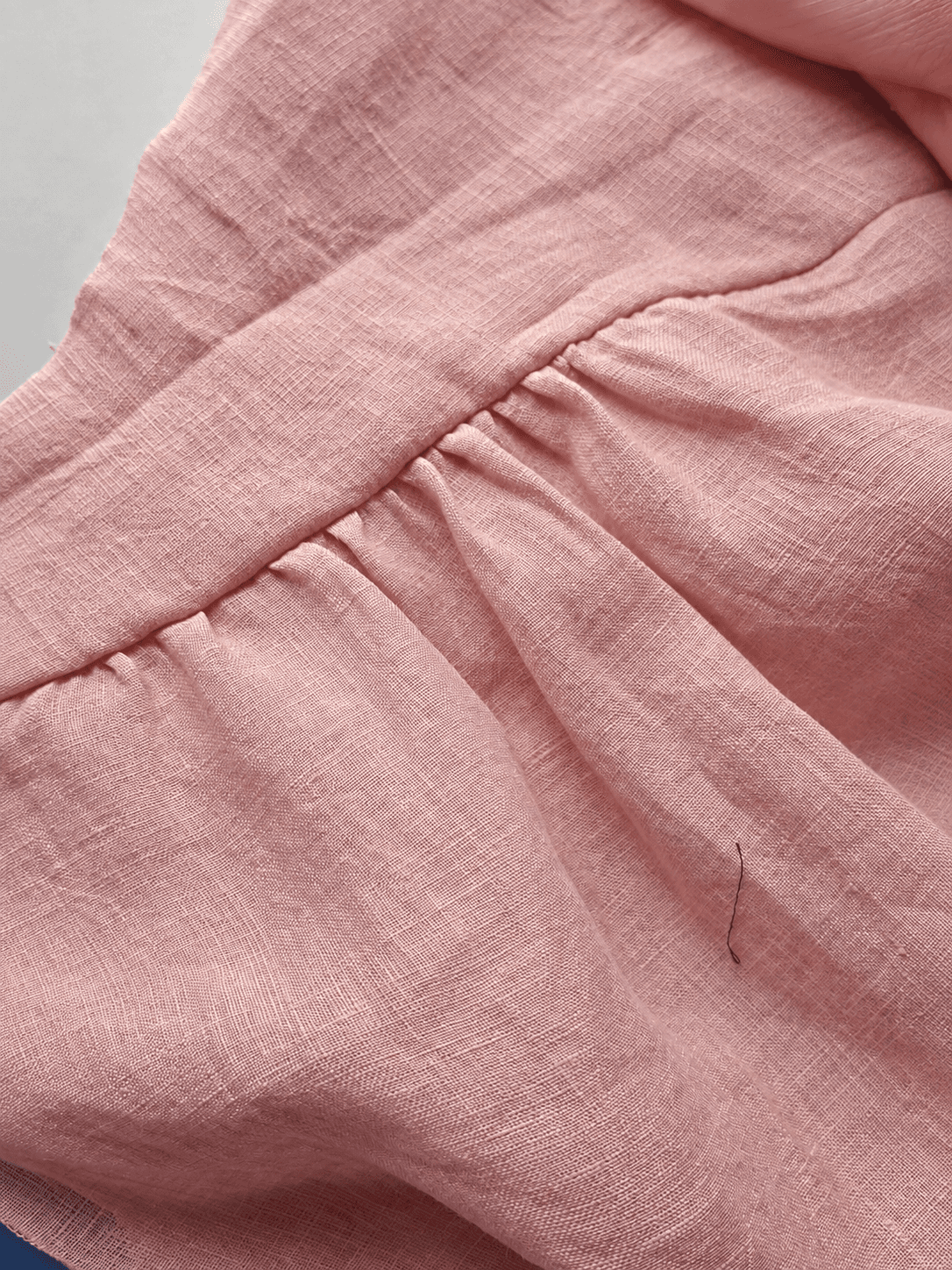 Gathered dusty-rose linen detail during garment construction
