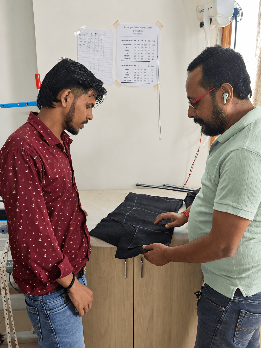 Two makers reviewing chalk-marked black garment pieces